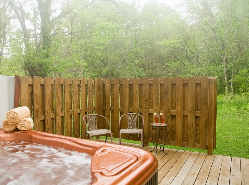 A private hot tub oasis with a wooden fence and comfortable seating, perfect for relaxation in a pea