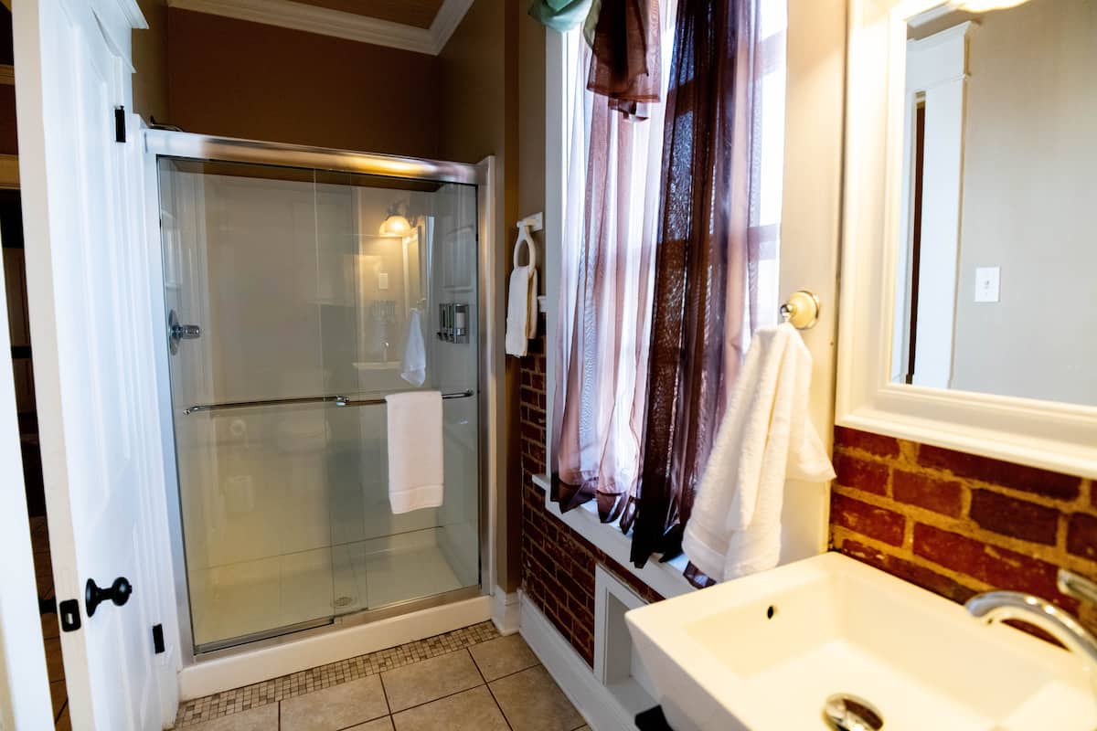 This bathroom features a glass-enclosed shower, a sink with a white basin, a mirror, and exposed br