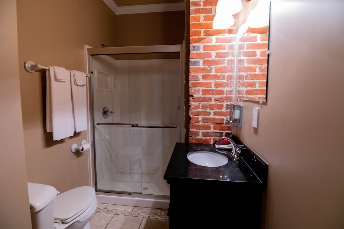 This functional bathroom features a glass-enclosed shower, a toilet, a vanity with a dark counterto