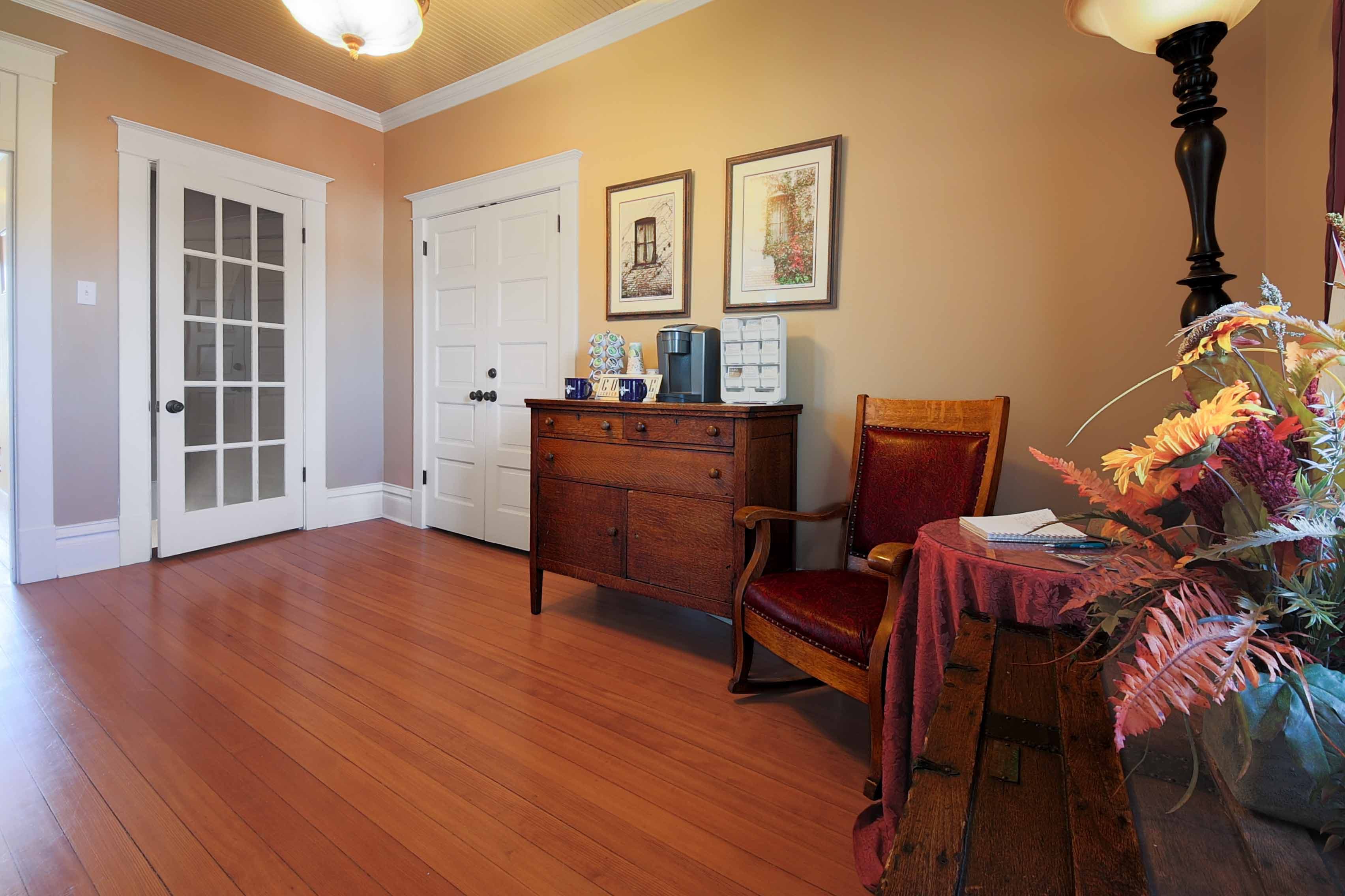 An inviting sitting area featuring gleaming hardwood floors, a dark wood dresser, a wooden chair, a