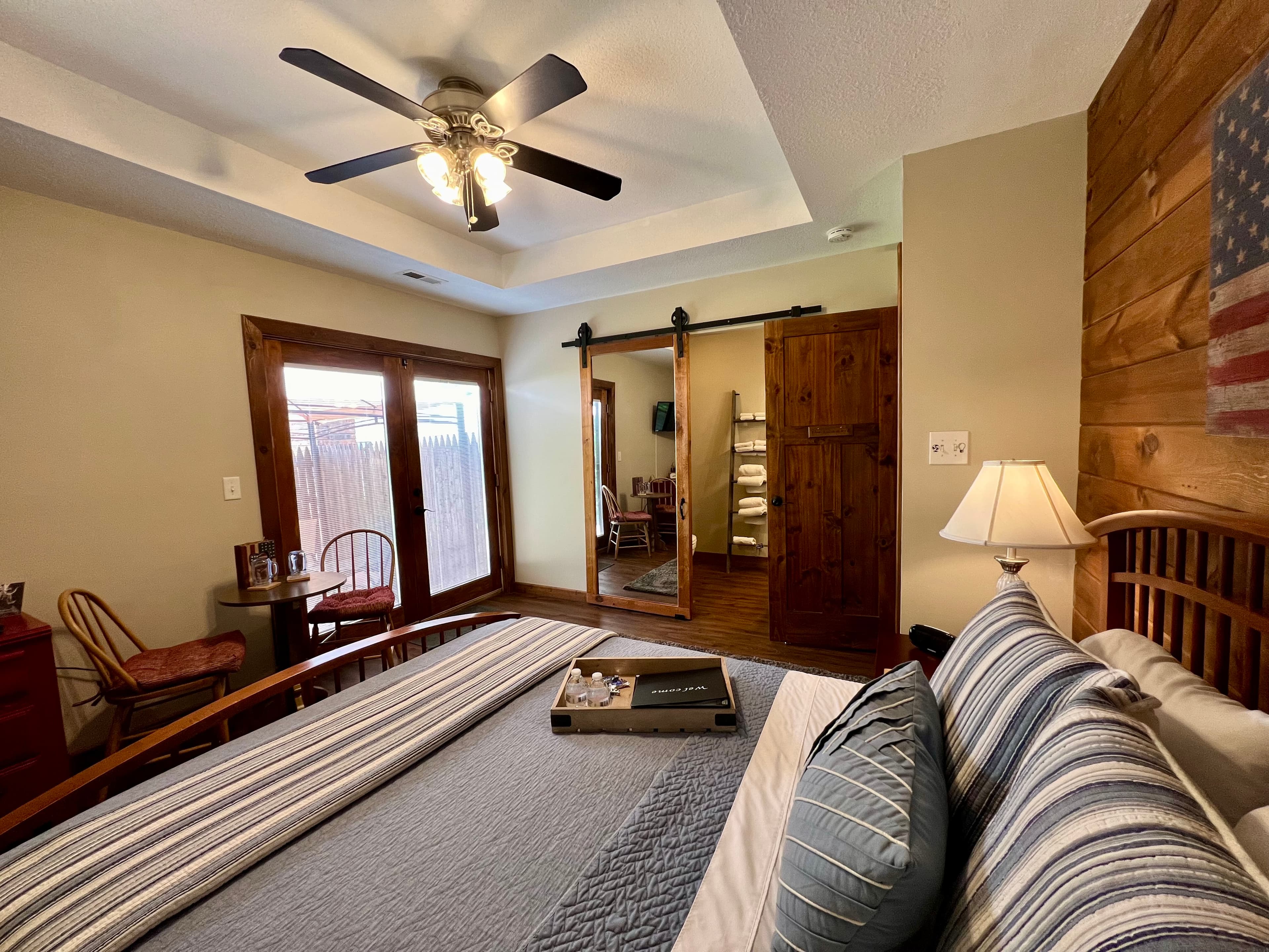 grey vanity with large mirror and silver lights above, ladder style towel rack with white towels