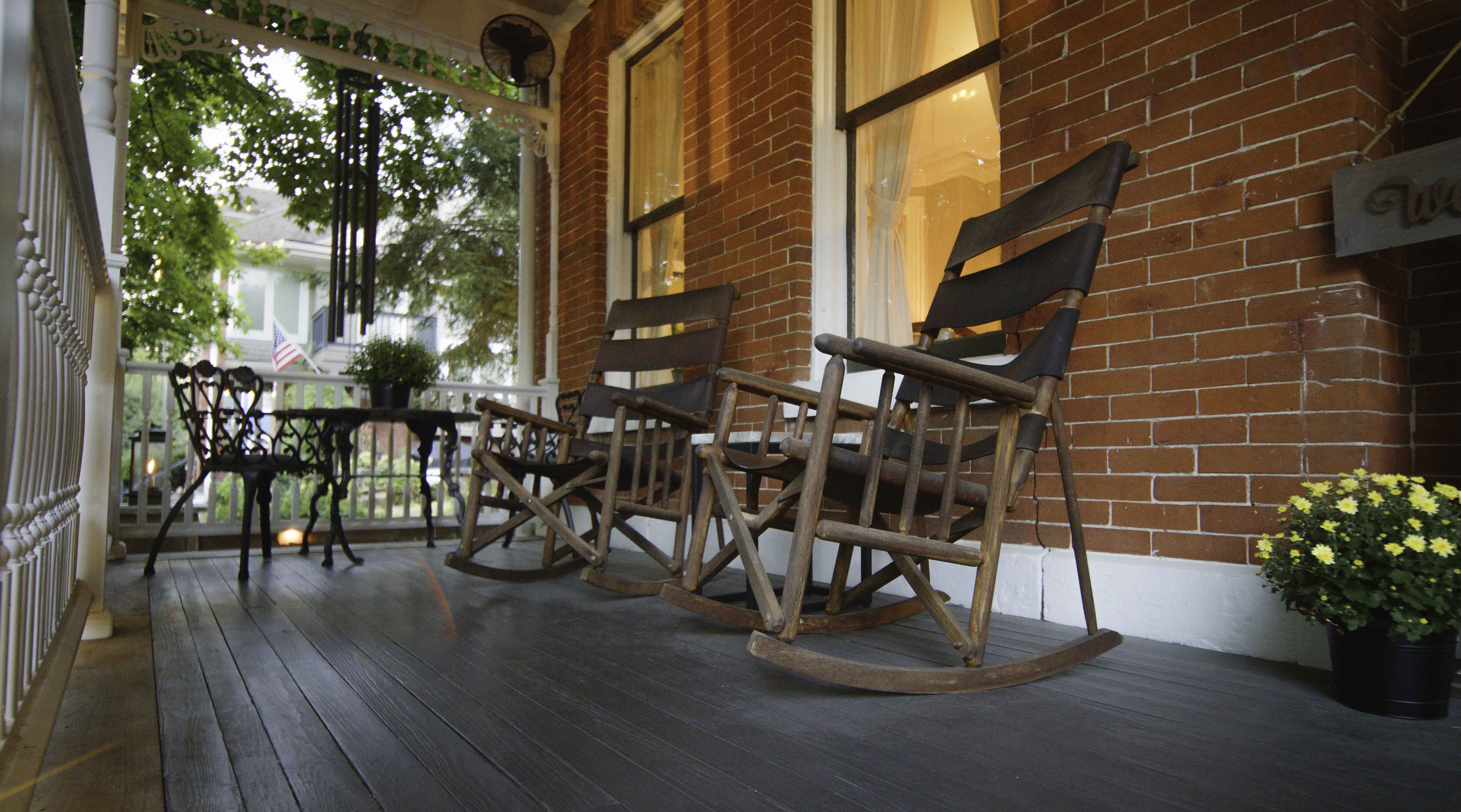 A cozy porch with rocking chairs, a small table, and potted plants.
