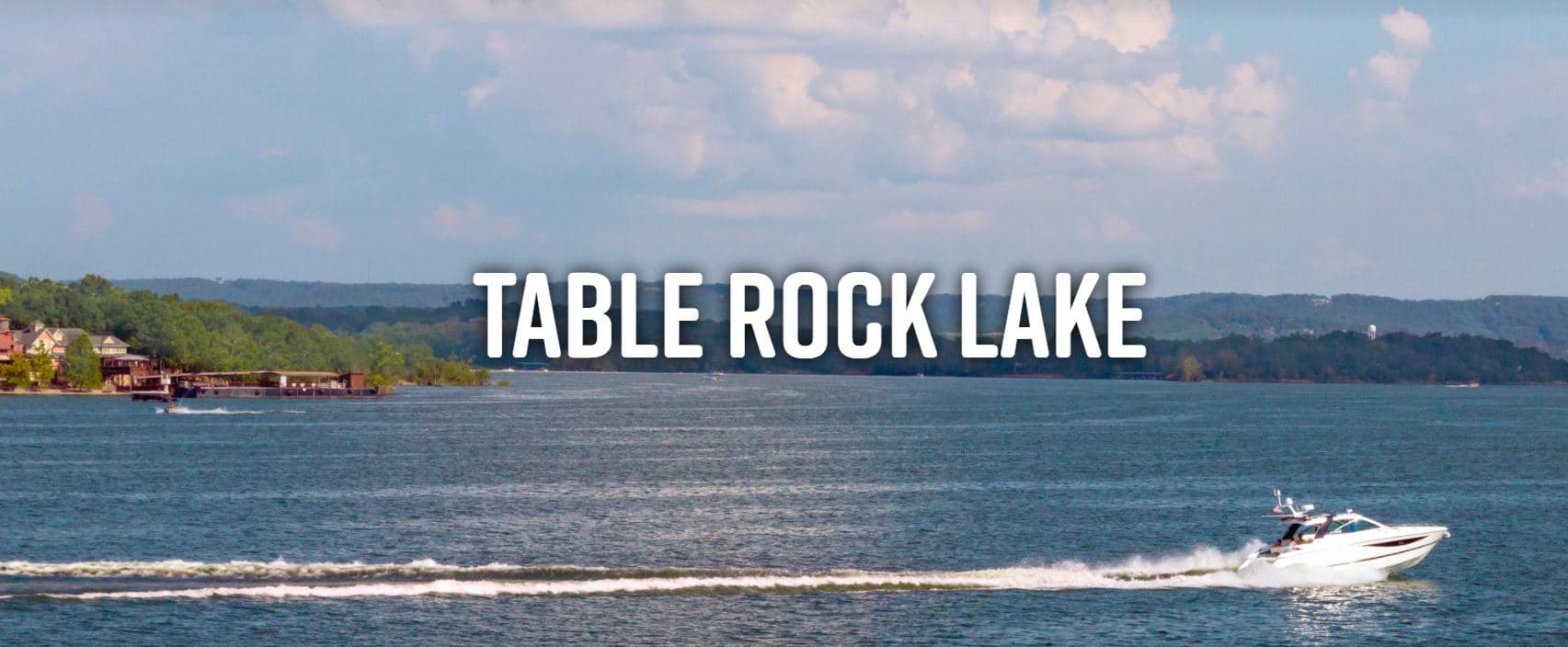 A motorboat glides across the tranquil waters of Table Rock Lake under a partly cloudy sky.