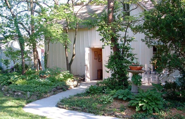A quaint house surrounded by greenery and a walking path.