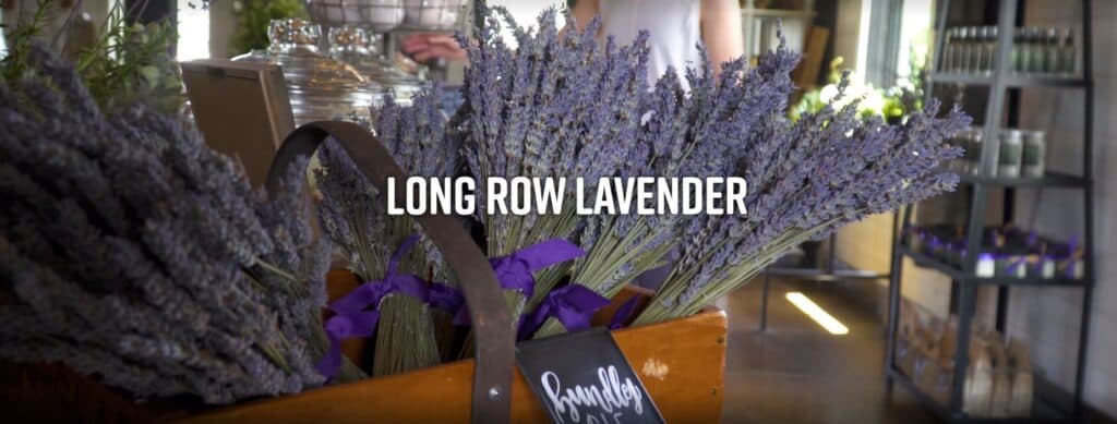 A wooden basket filled with dried lavender bundles, with "Long Row Lavender" displayed prominently above.