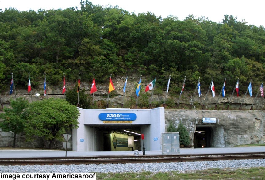 Entrance to a cave-like structure with multiple international flags displayed along the hillside.