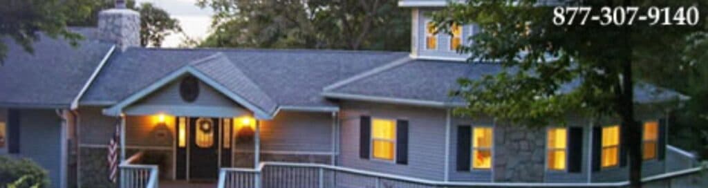 A well-lit, modern house with a stone accent and a welcoming front porch.