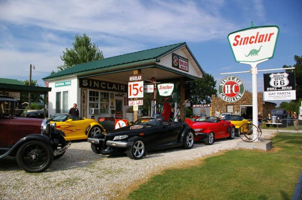 A vintage Sinclair gas station with classic cars parked outside on Route 66.