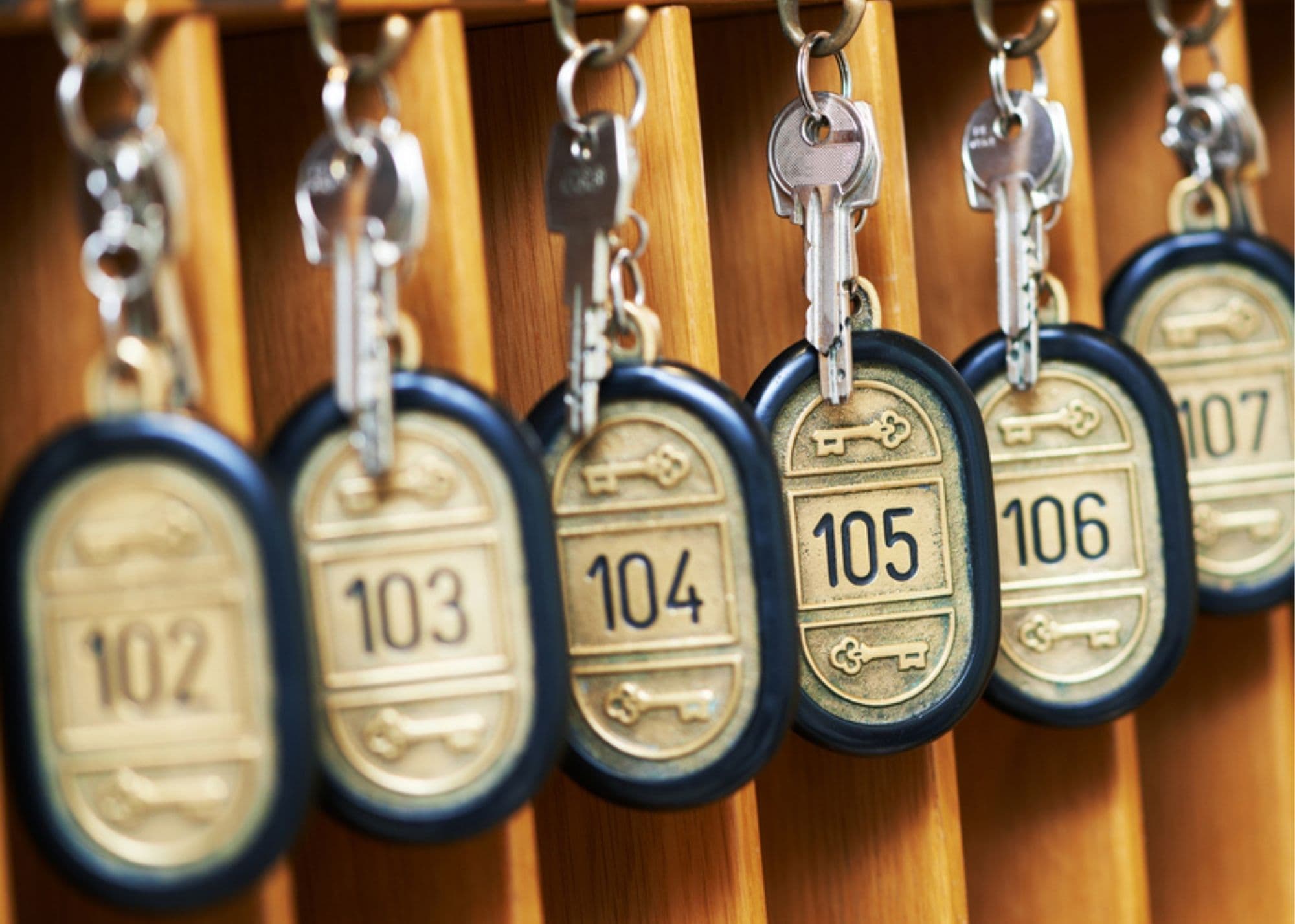 A row of vintage hotel keys labeled with room numbers 102 to 107.