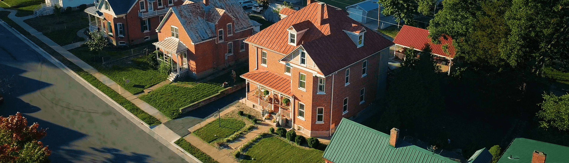 Aerial view of a neighborhood featuring brick houses with colorful roofs and manicured lawns.