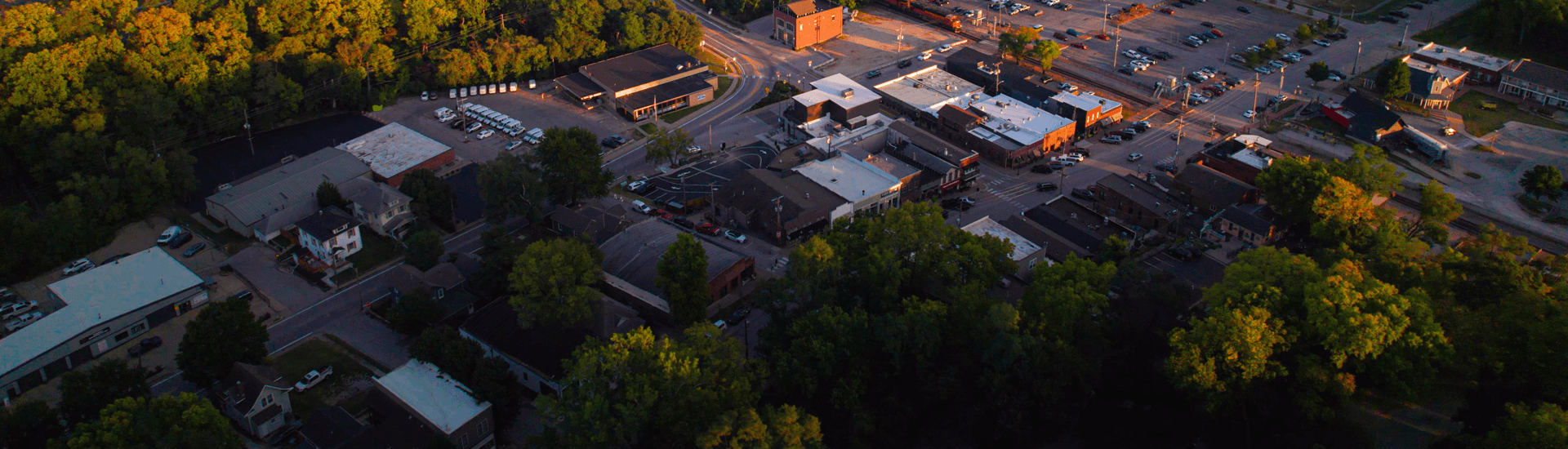 Aerial view of a small town with tree-lined streets and a bustling commercial area.
