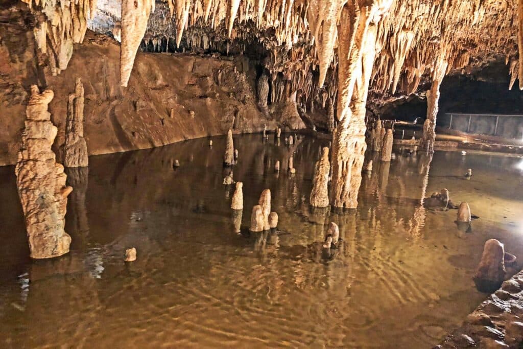 Stalactites and stalagmites reflect in a tranquil underground pool within a cave. Stalactites and stalagmites reflect in a tranquil underground pool within a cave.