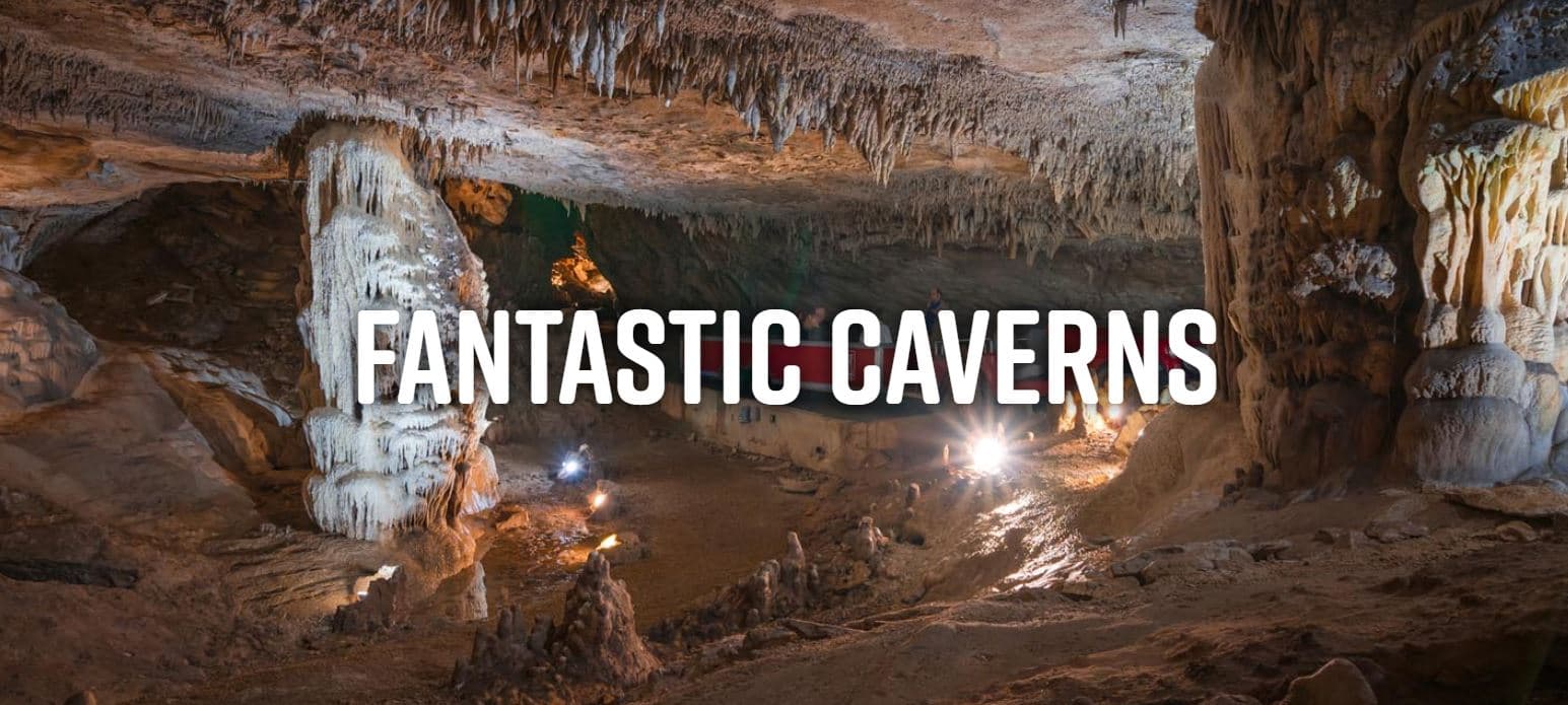 A dimly lit cavern with stalactites and stalagmites, featuring the text "FANTASTIC CAVERNS."