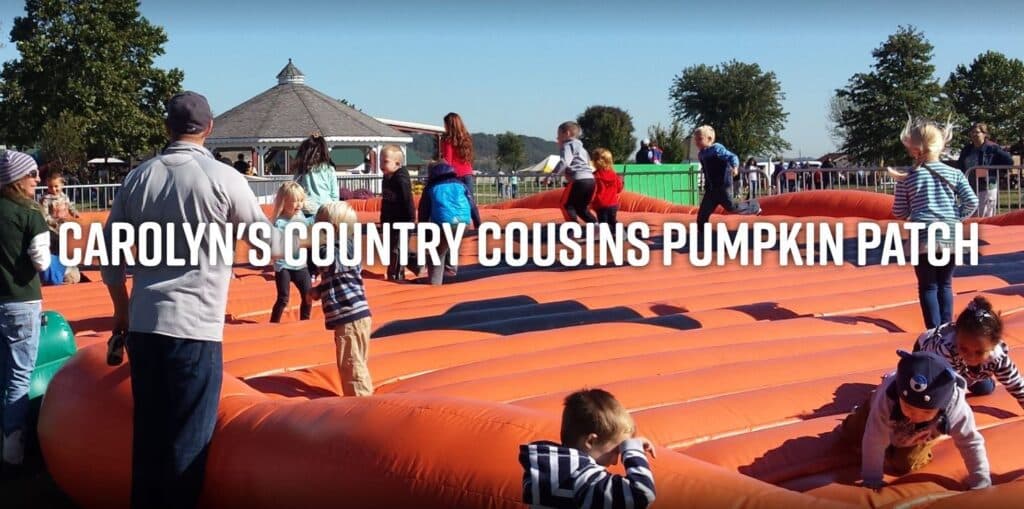 Children and adults enjoy a large inflatable in a pumpkin patch setting.