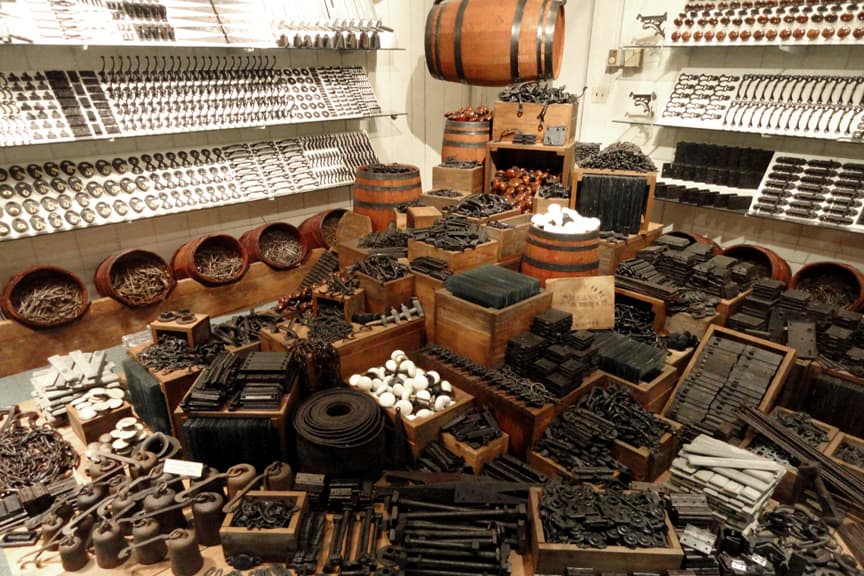A cluttered display of various antique hardware and tools arranged on shelves and tables.