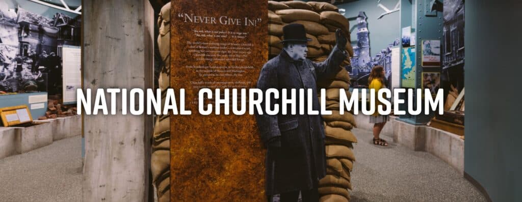 A display at the National Churchill Museum featuring a figure of Winston Churchill beside a "Never Give In" plaque.