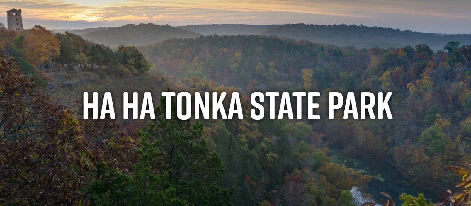 A scenic view of Ha Ha Tonka State Park with lush trees and rolling hills under a dusk sky.